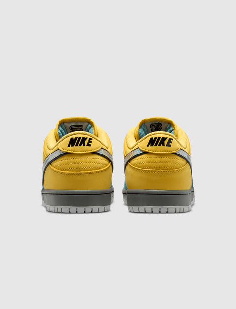 Yellow low-top sneakers with gray soles and black NIKE logo, rear view on white background