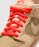Close-up of tan Nike SB Dunk Low Pro sneaker with woven texture and bright red laces