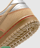Close-up of beige and silver sneaker heel with textured upper, red stitching, and detailed sole
