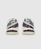 Rear view of cream and purple athletic sneakers with silver accents on light background