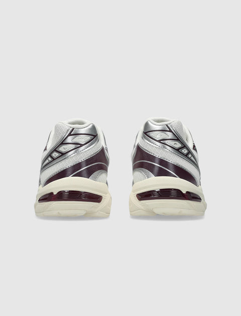Rear view of cream and purple athletic sneakers with silver accents on light background