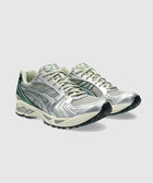 Silver and green mesh running sneakers with textured sole on a light grey background
