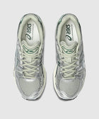 Overhead view of silver and green mesh Asics running sneakers on a light gray background