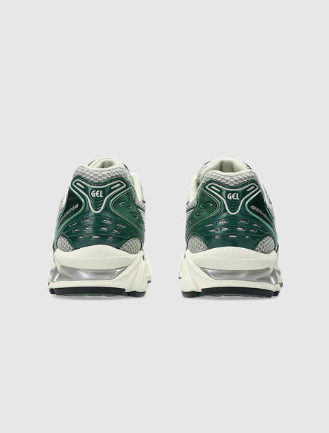 Rear view of green and white athletic sneakers with mesh and gel cushioning details
