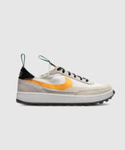 White and beige low-top sneaker with orange swoosh, black laces, and green pull tabs