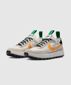 Men's streetwear sneakers with beige upper, orange swoosh, green pull tabs, and black laces