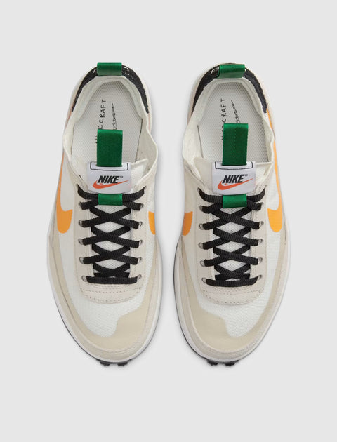 White and beige sneakers with orange swoosh and green pull tab, top view