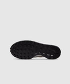 Black waffle sole of a lifestyle sneaker on a gray background