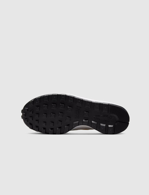 Black waffle sole of a lifestyle sneaker on a gray background