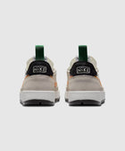 Back view of beige, black, and green low-top sneakers with chunky white soles
