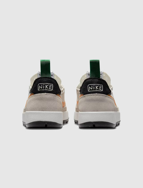 Back view of beige, black, and green low-top sneakers with chunky white soles