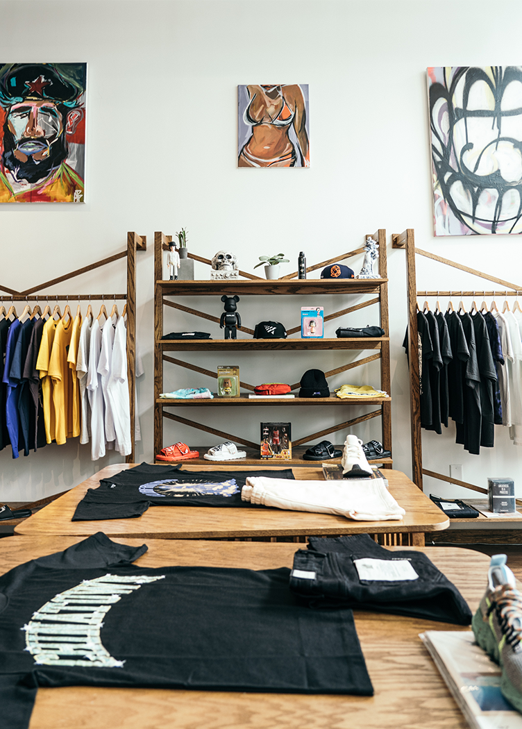 Men’s streetwear store interior with colorful t-shirts, sneakers, and art on the walls.