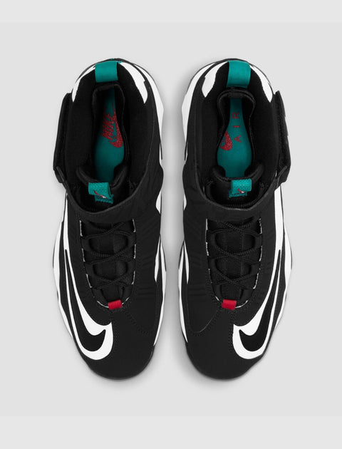 Black and white athletic sneakers with teal tongue tab, red logo, and bold swoosh design