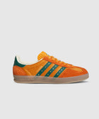 Orange and green low-top sneaker with suede details and gum sole on a light background