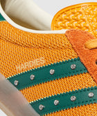 Close-up of orange mesh sneaker with green leather stripes, rhinestone accents, and 'HARDIES' text