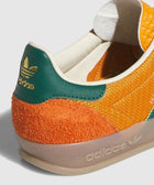 Close-up of orange and green Adidas sneaker heel with gold logo, suede and leather details