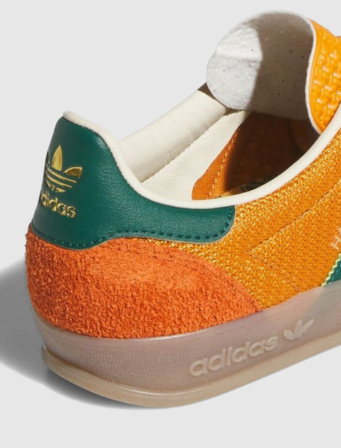 Close-up of orange and green Adidas sneaker heel with gold logo, suede and leather details