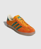 Orange and green low-top sneaker with suede upper, gum sole, and striped side detailing