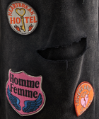 Close-up of black streetwear fabric with embroidered patches and a distressed rip