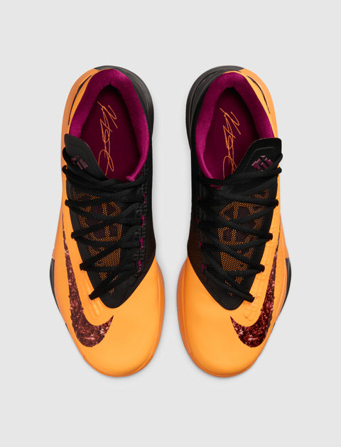 Top view of orange and black men's sneakers with purple interior and textured Nike swoosh.
