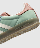 Close-up of green and brown suede sneaker with white stripes and gum sole, retro style