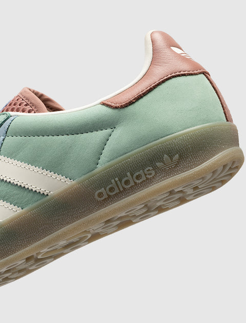 Close-up of green and brown suede sneaker with white stripes and gum sole, retro style
