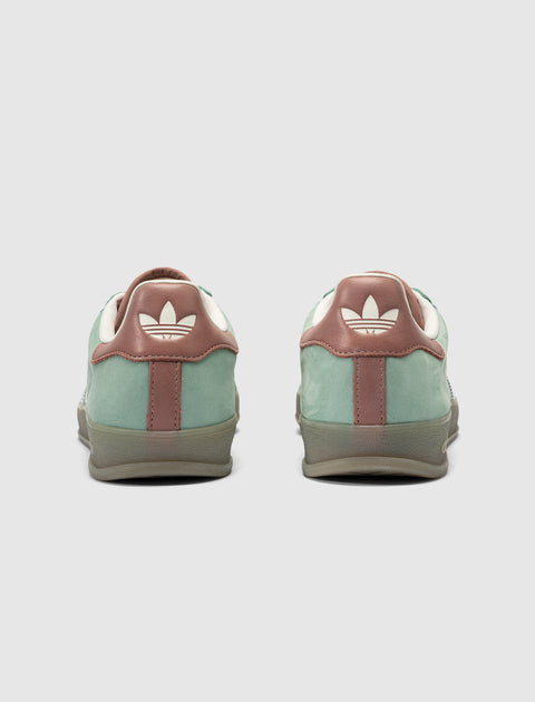 Rear view of green and brown suede sneakers with white logo on heel tab on white background.