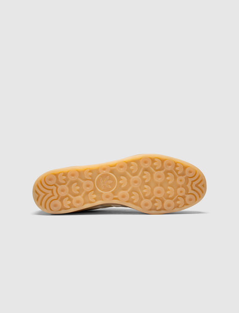 Gum sole sneaker bottom with circular traction pattern and logo, viewed on white background