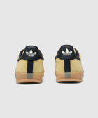 Yellow and navy suede sneakers with gum soles, rear view on white background