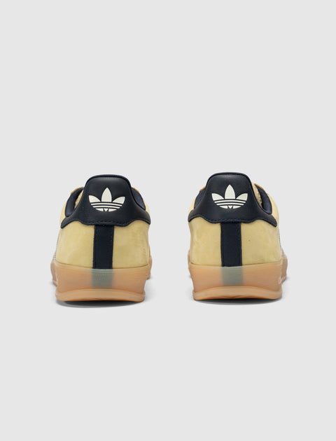 Yellow and navy suede sneakers with gum soles, rear view on white background