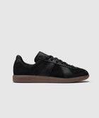 Black low-top sneaker with suede upper and brown gum sole, minimalist streetwear shoe
