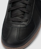 Close-up of black leather sneaker with gum sole and black laces