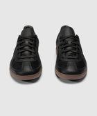 Pair of black low-top sneakers with gum soles on a plain background