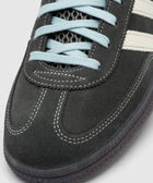 Close-up of grey suede sneaker with cream stripes, blue laces, and textured sole