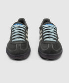 Front view of grey suede sneakers with cream stripes and blue laces, on white background.