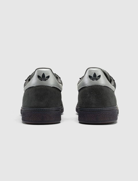 Gray and cream suede low-top sneakers, viewed from the back, with black logo on heel tab