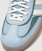 Close-up of blue suede sneaker with white laces, mesh tongue, and gum outsole