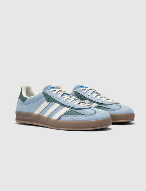 Light blue and green low-top sneakers with white stripes and gum sole on plain background