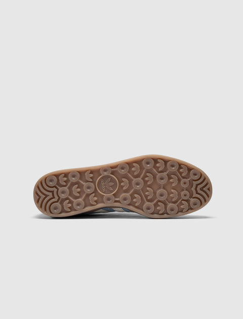 closeup of gum sole with circular tread pattern on blue and green sneaker