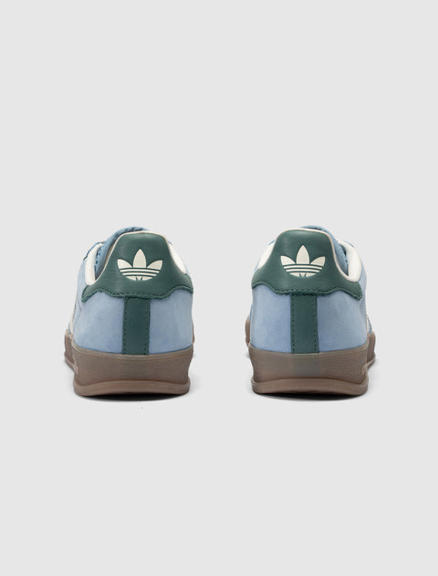 Blue and green low-top sneakers with white logo on heel and gum sole, rear view