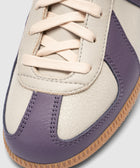 Close-up of a cream and purple leather sneaker with beige laces and gum sole