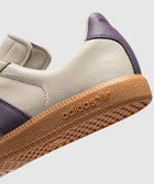Closeup of beige and purple sneaker with gum sole and adidas logo, men's streetwear shoe
