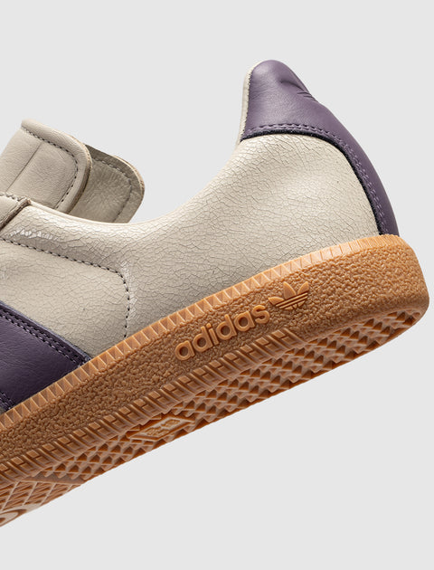 Closeup of beige and purple sneaker with gum sole and adidas logo, men's streetwear shoe
