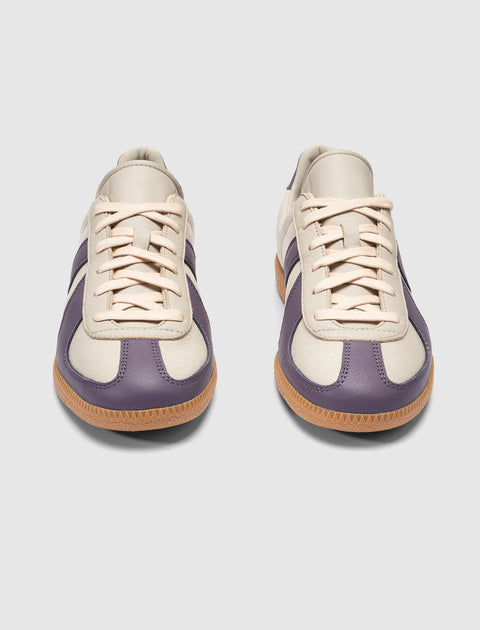 Pair of cream and purple low-top sneakers with gum soles on a plain background