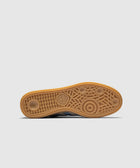 Gum sole of a sneaker with textured grip pattern and adidas logo, gray blue upper visible