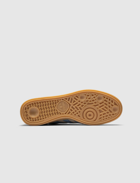 Gum sole of a sneaker with textured grip pattern and adidas logo, gray blue upper visible