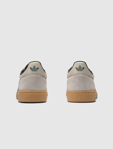 Rear view of grey and blue suede sneakers with gum soles and teal heel logo