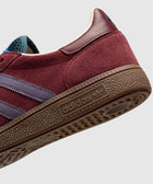 Close-up of burgundy suede sneaker with purple stripes and brown gum sole