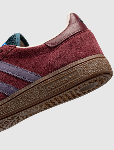 Close-up of burgundy suede sneaker with purple stripes and brown gum sole