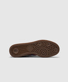 Brown adidas sneaker outsole with textured grip and logo, photographed on a white background